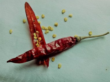 Baharatlı kırmızı biberler beyaz arka planda izole edilir. Kırmızı biberler kırmızı ve parlak renklidir. Gözyaşları içinde açılır ve açılır ve tohumlar arka planda yayılır..