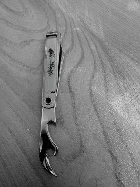 Çivi kesicinin ahşap bir masanın üstüne yerleştirilmiş olması. Tırnak kesicinin içinde parmakları temizlemek için birçok seçeneği vardır. Keskin bir bıçak kenarı ve pürüzsüz kenarlı bıçakları vardır..