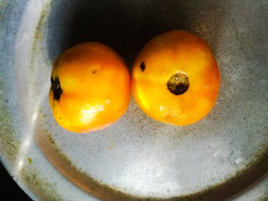 Alüminyumdan yapılmış tabağa yerleştirilmiş olgun domatesler. Domateslerin tepesinde koyu bir leke vardır..