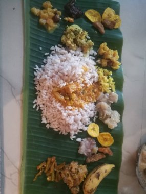 Kerala usulü Onam Sadhya 'nın üst açı görüntüsü muz yapraklı köri ile. Yaprak pirinçle kaplıdır ve farklı yemeklerle çevrilidir. Muz yaprağının yeşil rengi koyu renklidir..