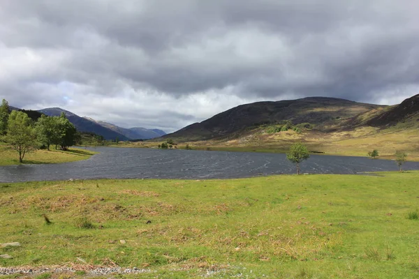 Dağların önünde İskoç gölü ve çayırları