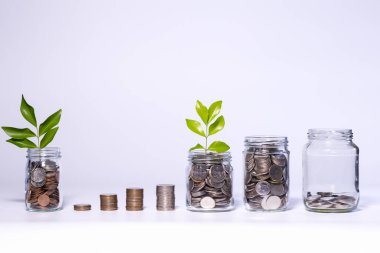 Beyaz arkaplana sürahi bardağa bozuk para koyarak tasarruf etmek