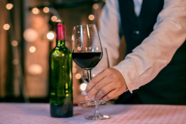 Garson adam bardağa şarap dolduruyor.