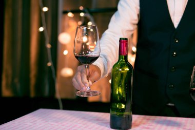 Garson adam bardağa şarap dolduruyor.