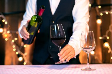 Garson adam bardağa şarap dolduruyor.