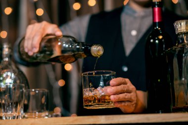 Barmen viski bardağı dolduruyor.