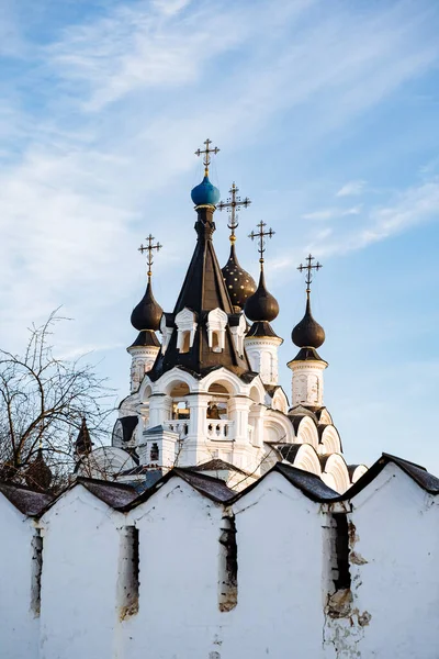 White beautiful Orthodox Church under construction in winter time. Snowy panorama of blue sky and christian church with golden domes.