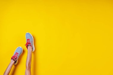 Spor ayakkabıları sarı arka planda, kırmızı bağcıklar, moda blogu ya da dergisi konsepti, minimalist ayakkabı arka planı, spor