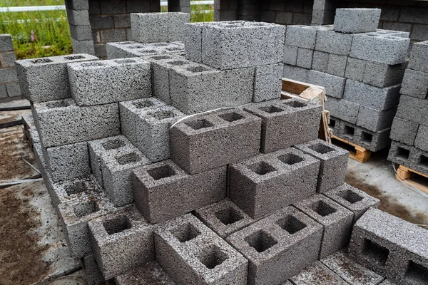 Gri beton tuğlalar düzgün bir şekilde yığılmış. İnce tuğlalar, bir ev inşa etmek için malzeme.