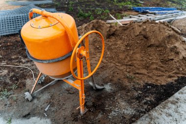 İnşaat için çimento hazırlanan turuncu beton karıştırıcı sokakta duruyor.