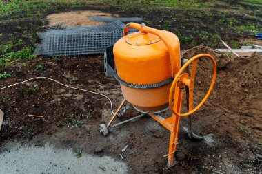 an orange concrete mixer where cement is prepared for construction works stands on the street