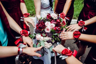 Gelin ve nedimelerin buketi, nedimeler düğün buketinin etrafında duruyorlar, bir kadının elinde çiçek bileziği.