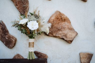 Gelin buketi, düğün buketini elinde tut, saten kurdeleler gül buketini süsle, gelinin elbisesinin arka planında, bir çiçekçi tarafından yapılan taze çiçekler,