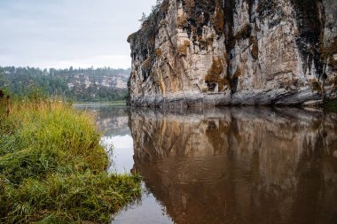 Nehre düşen kaya, taştan uçurum, nehirde sabah, sis, bulutlu havada manzara, Rusya Güney Urallar Yuryuzan nehri, Rusya 'nın doğası.