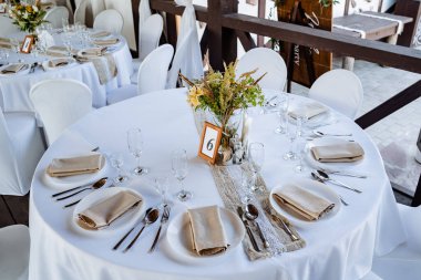 Bayram masası, masaya tabak koymak, beyaz masa örtülü bir ziyafet masası, bayram için yemek masasını hazırlamak, görgü kurallarına göre düzenlenir. Masadaki çiçekler.