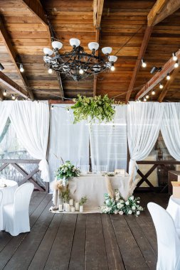 Düğün masasının dekorasyonunda çiçekler ve mumlar, düğün dekorasyonu, doğal malzemelerden yapılmış masa örtüsü, masa takımı..