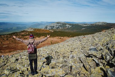 Adam kollarını dağlarda açtı. Genç bir adam dağları seyretmekten hoşlanır. Etraftaki güzelliği görmenin zevki. Ural Dağları.