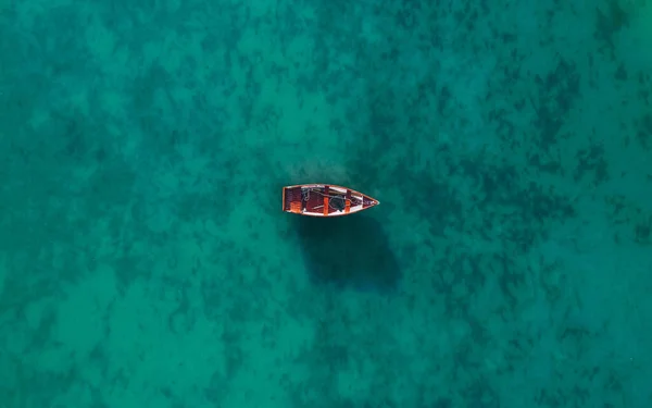 Aerial view of a wooden boat in the water, ship and boat in a beautiful turquoise ocean near an island, top view, aerial photo