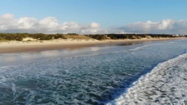 Erken gün batımı sıcak güneş ışığı ve sakin dalgalar kıyıya haddeleme kumlu plajı ile boş Yalı