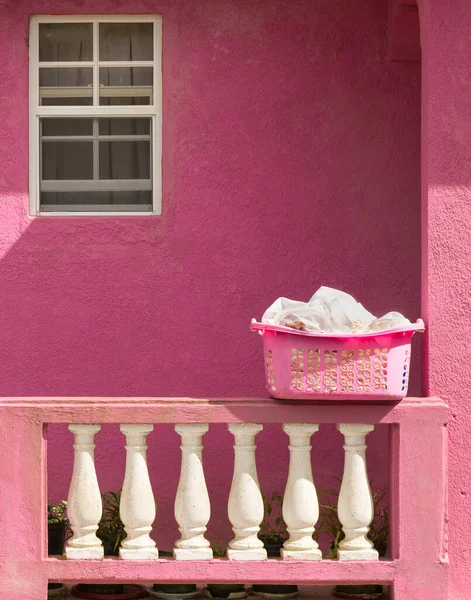 Pink building in the Caribbean with a pink laundry basket on the porch