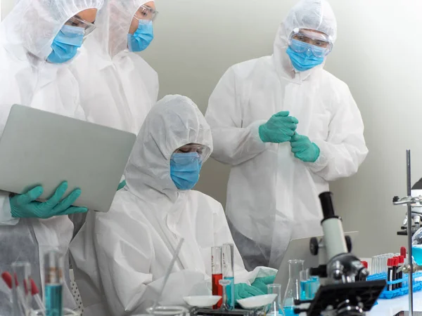 Asian scientist team in personal protection equipment or PPE suit are discussing about treatment of patient with coronavirus in protective room. Pandemic infectious concept.