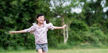 Açık çayırlarda koşan Asyalı bir kız.