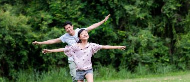 Açık otlaklarda koşan Asyalı tatilde mutlu bir aile.