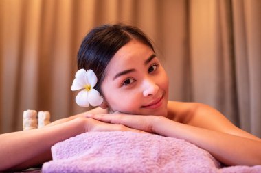 Genç bir kadın kaplıcada bitki torbalarıyla masaj yaptırıyor.