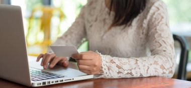 Kredi kartı tutan ve online alışveriş ve ödeme için dizüstü bilgisayarda yazan genç kadın İnternet, Çevrimiçi ödeme, İşletme finans ve teknoloji üzerinden satın alıyor