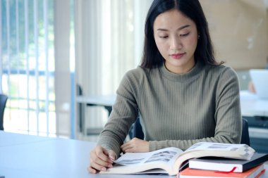 Öğrenciler sınıfta kitap okurlar. Üniversitede üniformalı Asyalı bir öğrenci kitap okuyor.