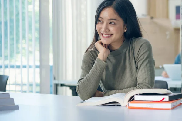 Öğrenciler sınıfta kitap okurlar. Üniversitede üniformalı Asyalı bir öğrenci kitap okuyor.