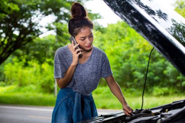 Stresli bir adam Stresli bir adamın stree 'deki araba arızasından sonra otururken cep telefonu kullanan Asyalı kadın.