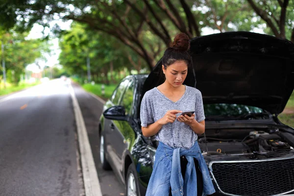 Asian woman using mobile phone while looking and Stressed man sitting after a car breakdown on stree