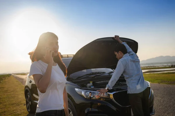 Couple on the road having problem with a car.Couple after a car