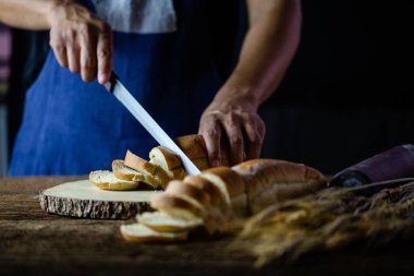 Erkek eller tahtanın üzerinde buğday ekmeği kesiyor. Geleneksel ekmek dilimlere bölünür