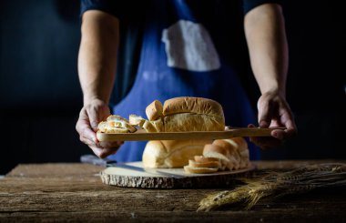 Erkek eller tahtanın üzerinde buğday ekmeği kesiyor. Geleneksel ekmek dilimlere bölünür