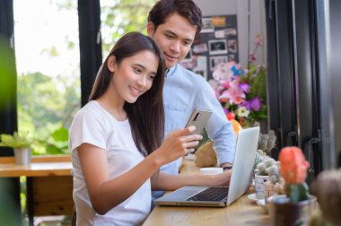 Kafede dizüstü bilgisayarla çalışan Asyalı genç kız ve adam.