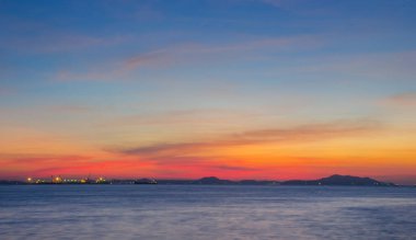 Gökyüzü, akşam günbatımında parlayan turuncu ışık, gökyüzünün rengi bulutlu olur, gölün ve adaların üzerindeki alacakaranlık sahnesi, gece parlayan ışıklarla, arka plan görüntüsüyle.