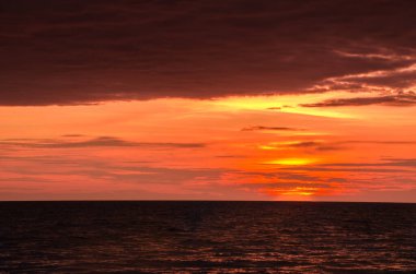 Pastel rengarenk denizde gün batımı ve akşamları bulutlar.