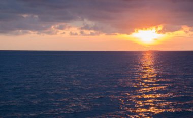 Derin mavi gökyüzü ve güneş ışınlarıyla renkli okyanus plajı gündoğumu.