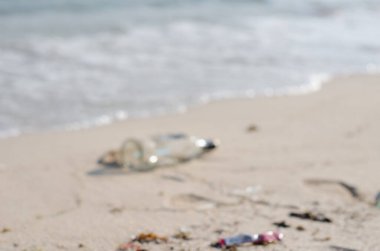 Plajda kullanılan çöp şişeleri, çevresel kirliliğin başlangıcı, deniz ekosistemleri bulanık görüntü