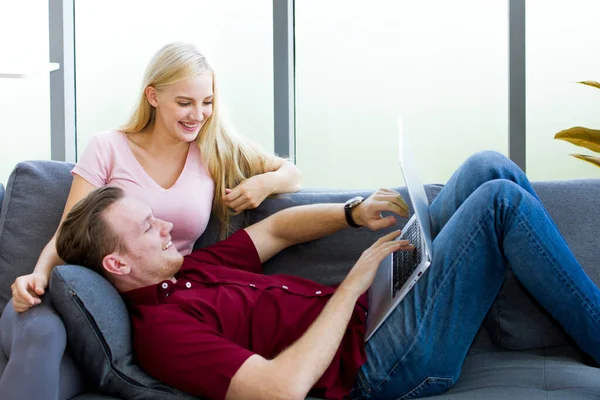 Young couples watching multimedia or video streaming online on a laptop, a Young man lying on his girlfriend\'s lap and pointed at the screen.