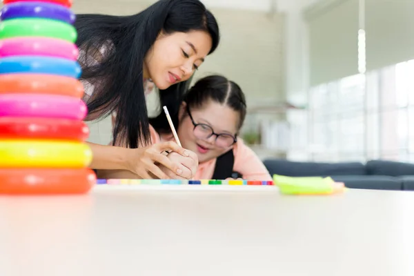 Mom is teaching an autism daughter to write her own name by holding her hand. Training for intelligence restoration for children with autism or aphasia kids.