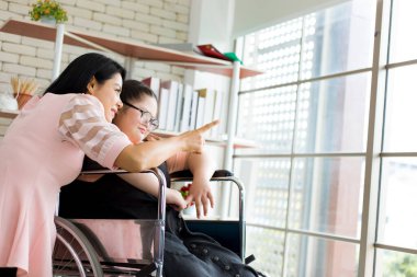Anne, tekerlekli sandalyede oturan ve evde afazi yüzünden hasta olan kızına bakıyor. Annem otizmli çocuklar için istihbarat yenileme eğitimi vermeye ve pratik yapmaya çalışıyor..