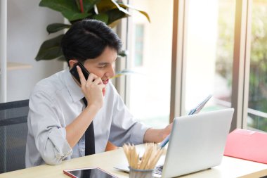 Asyalı erkek çalışan ya da girişimci telefonda bir müşteriyle konuşuyor. Tele-pazarlamacı kavramı.