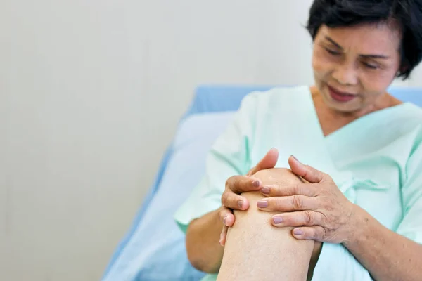 Older women have knee pain due to osteoarthritis or Gout disease. Elderly female using her hand to grasp the injured knee.