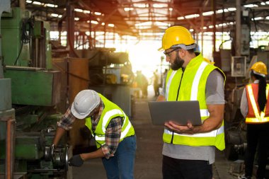 Teknisyenler fabrikadaki makinelerin hazır olup olmadığını kontrol ediyorlar. Üretim sürecine başlamadan önce iki mühendis güvenlik standartlarını denetliyor..