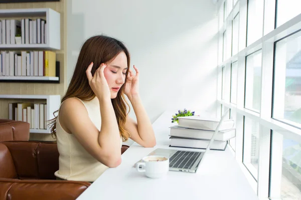 A high school student is having a headache while doing a report in the library. The freelance woman is stressed over rethinking work inside the cafe.