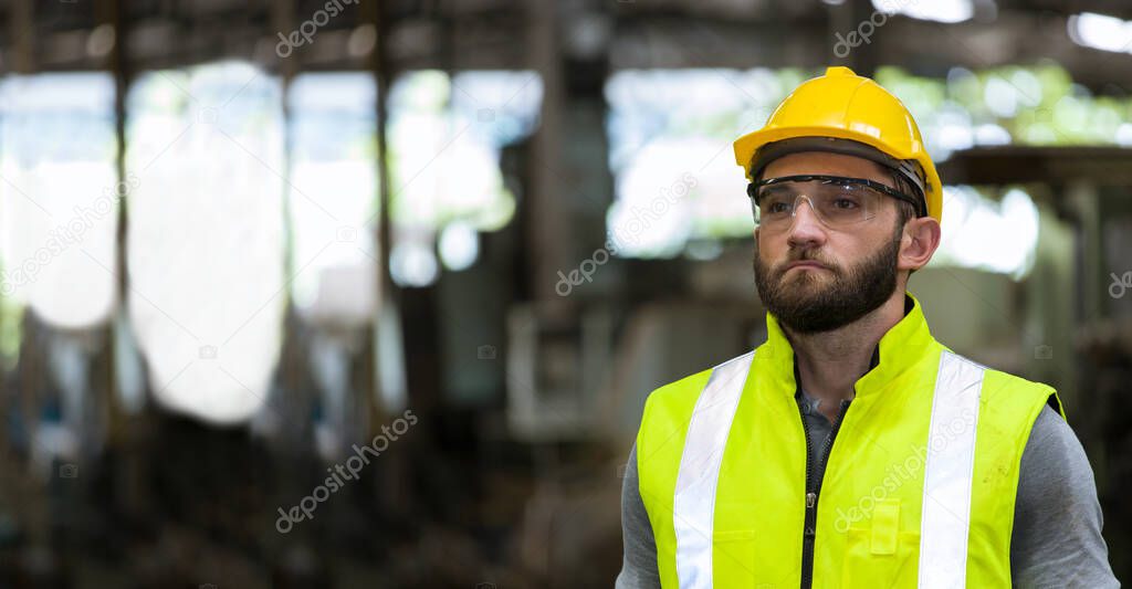 Portrait of the caucasian handsome bearded engineer, He was wearing safety gear and standing in the factory.