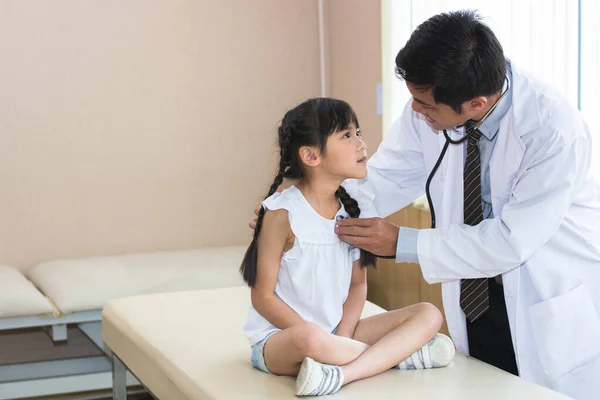 Doctor is a physical exam for the child girl in the examination room.